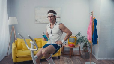 Spor bisikleti eğitimi ve spor şişesini oturma odasında tutma, retro spor konsepti