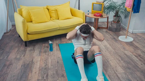 スポーツマンがリビングルームのフィットネスマットで腹筋運動をする — ストック写真