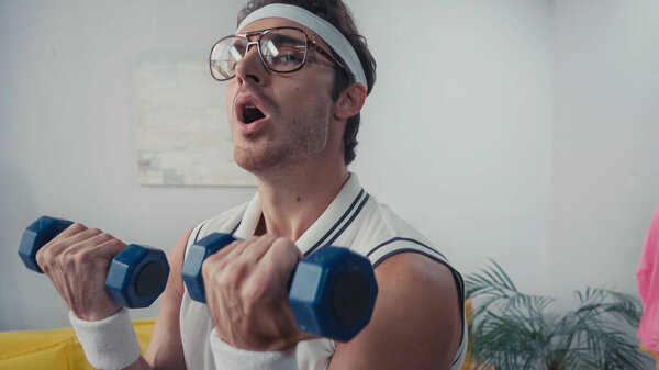 tired man exercising with dumbbells at home, retro sport concept 