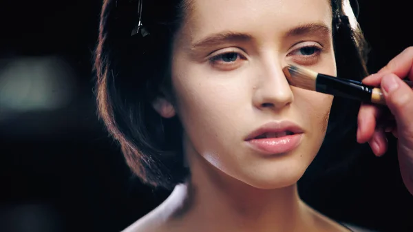 Artista de maquiagem aplicando fundação de maquiagem na pele do modelo com escova cosmética — Fotografia de Stock
