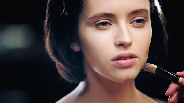 Makeup artist applying makeup foundation on face of brunette model — Stock Photo