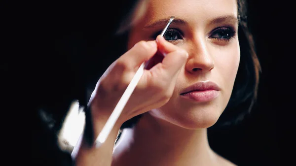 Makeup artist styling eyebrow on young woman — Stock Photo