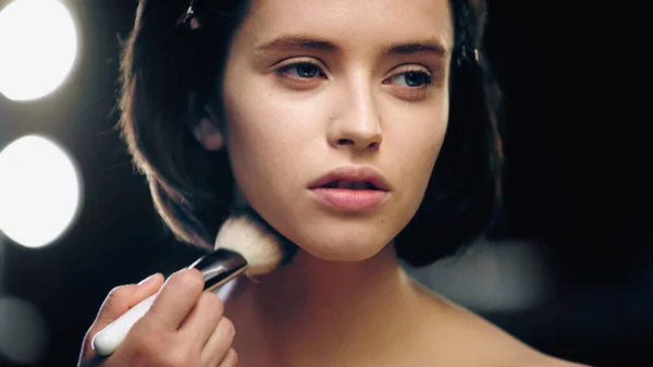 Makeup artist applying powder on face of pretty model — Stock Photo