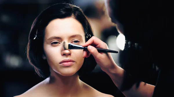 Maquillaje artista aplicar polvo en la cara de modelo morena - foto de stock