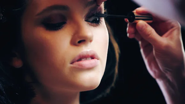 Make-up-Artist trägt schwarze Mascara auf Wimpern des Models auf — Stockfoto