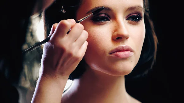 Maquilleuse coiffant les sourcils de la jeune femme — Photo de stock