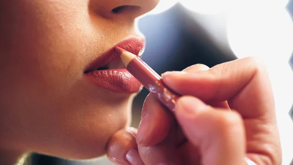 Vista recortada do artista de maquiagem aplicando lápis de lábio nos lábios do modelo — Fotografia de Stock