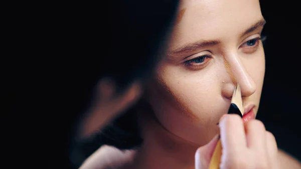 Maquilleuse floue faisant visage contouring de la femme avec pinceau cosmétique — Photo de stock