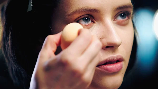 Maquiador aplicando fundação de maquiagem com esponja cosmética no rosto do modelo — Fotografia de Stock