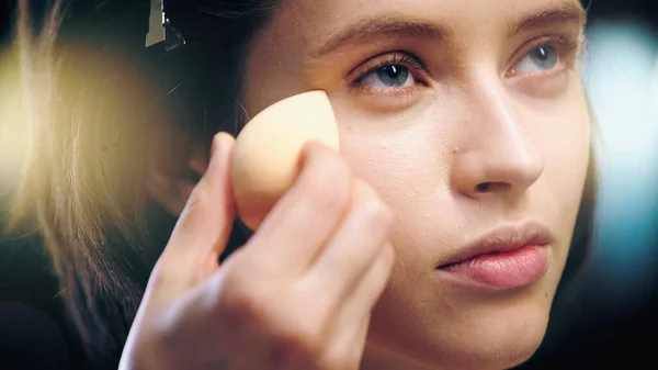 Maskenbildnerin trägt Make-up-Foundation mit Kosmetikschwamm auf Gesicht des Models auf — Stockfoto