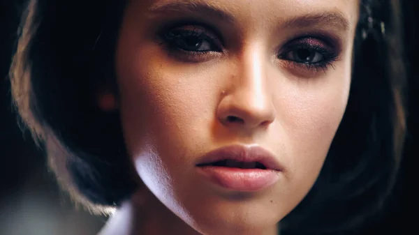 Close up of pretty and brunette model with makeup looking at camera — Stock Photo