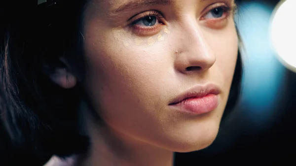 Concealer on face of young brunette model looking away — Stock Photo