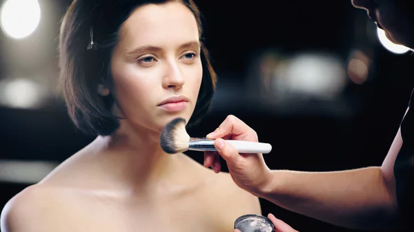 Makeup artist with cosmetic brush applying face powder on model — Stock Photo