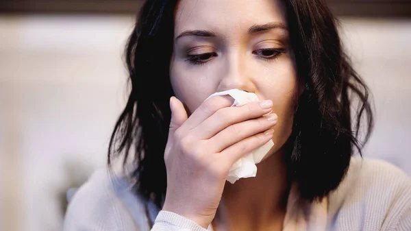 Vue rapprochée de femme bouleversée essuyant le nez avec une serviette en papier à la maison — Photo de stock