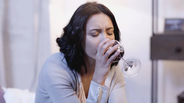 Femme seule buvant du vin rouge dans un verre avec les yeux fermés à la maison — Photo de stock