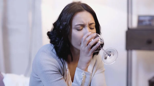 Lonely woman drinking red wine from glass with closed eyes at home — Stock Photo