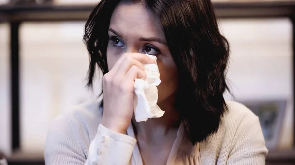 Crying brunette woman wiping tears with paper napkin at home — Stock Photo