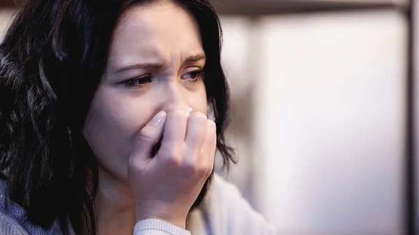 Portrait of upset brunette woman crying and covering mouth with hand at home — Stock Photo