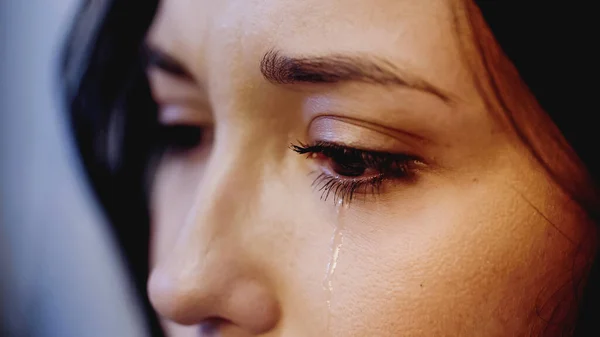 Vue rapprochée de femme bouleversée pleurant avec des larmes sur le visage sur fond gris — Photo de stock