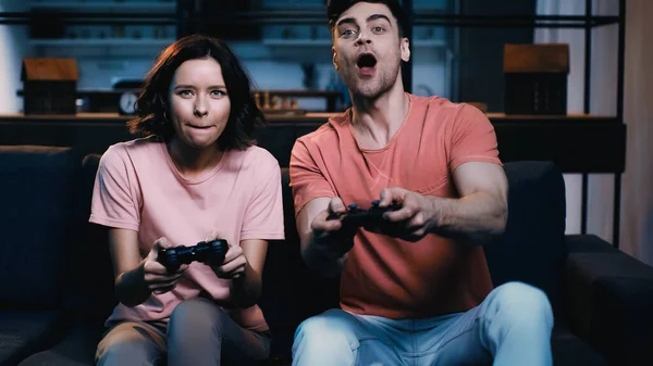 KYIV, UKRAINE - JUNE 09, 2021: amazed man and woman holding joysticks and playing video game — Stock Photo