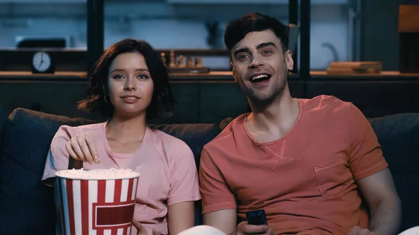 Glückliche Frau hält Popcorn-Eimer in der Hand und guckt Komödienfilm mit fröhlichem Freund — Stockfoto