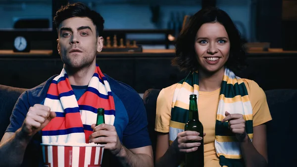 Happy sport fans sitting with bottles of beer and watching championship — Stock Photo