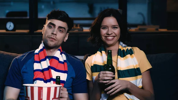 Happy and displeased sport fans sitting with bottles of beer and watching championship at home — Stock Photo