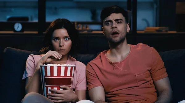 Brunette woman holding popcorn bucket and watching movie with boyfriend — Stock Photo