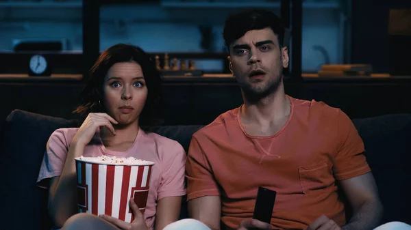 Femme manger du pop-corn et regarder un film avec petit ami choqué — Photo de stock