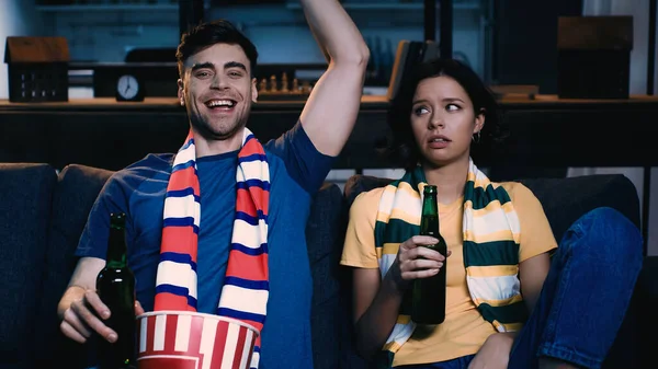 Homem feliz assistindo campeonato perto mulher descontente — Fotografia de Stock