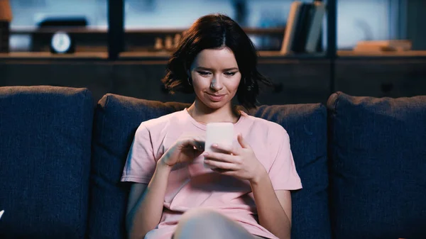 Brunette young woman using smartphone in living room — Stock Photo