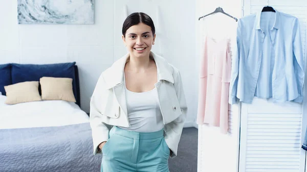 Junge Frau im lässigen Sommeroutfit posiert mit den Händen in den Taschen im Schlafzimmer — Stockfoto