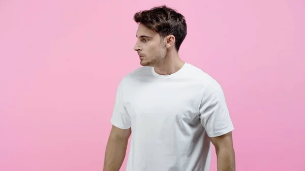 Vista lateral do homem com raiva em t-shirt branca olhando para longe isolado em rosa — Fotografia de Stock