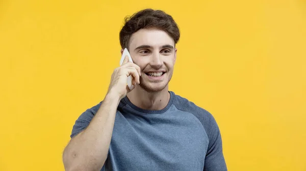 Усміхнений чоловік говорить на мобільному телефоні ізольовано на жовтому — стокове фото