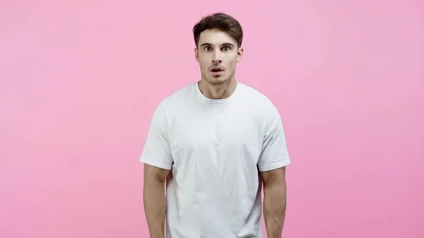 Удивительный мужчина в белой футболке смотрит в камеру, изолированную от розового — стоковое фото