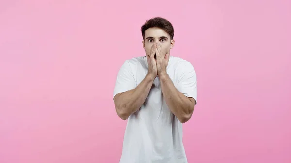 Verblüffter Mann bedeckt Mund isoliert auf rosa — Stockfoto