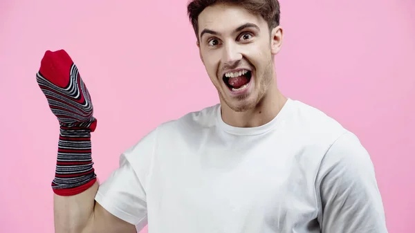 Erstaunter Mann mit Socke an der Hand, der in die Kamera schaut, isoliert auf rosa — Stockfoto