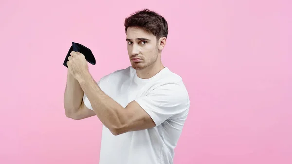 Upset man in white t-shirt holding empty wallet isolated on pink — Stock Photo