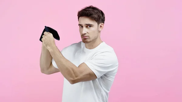 Homem perturbado em t-shirt branca segurando carteira vazia isolado em rosa — Fotografia de Stock