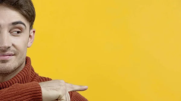 Vista cortada de homem sorridente em suéter apontando com o dedo isolado no amarelo — Fotografia de Stock