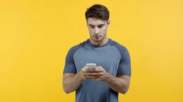 Захоплений чоловік використовує смартфон ізольовано на жовтому — стокове фото
