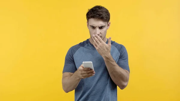 Homem ofendido usando telefone celular isolado no amarelo — Fotografia de Stock