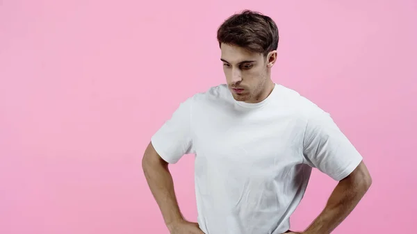 Homem pensativo em t-shirt branca de pé isolado em rosa — Fotografia de Stock