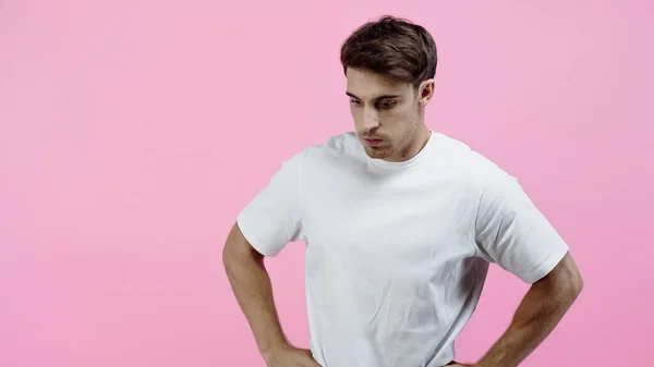 Hombre reflexivo en camiseta blanca de pie aislado en rosa — Stock Photo
