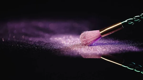 Soft cosmetic brush near dust with sparkling pink glitter on black — Stock Photo