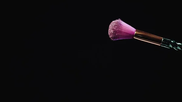 Pennello cosmetico morbido con polvere rosa scintillante isolato su nero — Foto stock