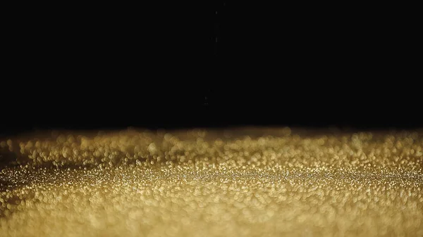 Polvo dorado brillante con brillo sobre fondo negro - foto de stock