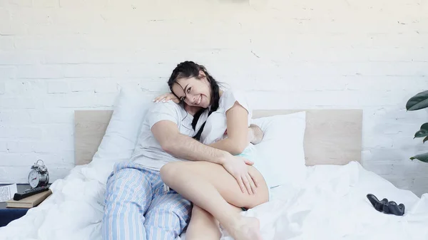 KYIV, UKRAINE - JUNE 17, 2021: cheerful woman hugging with man near joysticks on bed — Stock Photo