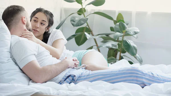 Mulher morena com tranças deitado e tocando rosto de namorado na cama — Fotografia de Stock