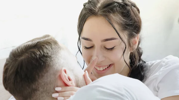 Boyfriend touching nose of cheerful brunette woman with braids — Stock Photo